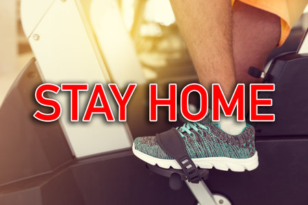 Sign Stay Home over man doing sports at gym background. Quarantine concept
