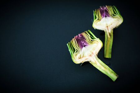 Fresh raw half cut artichokes on black background, flat layの写真素材