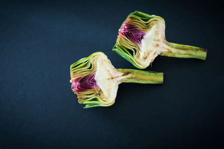 Fresh raw half cut artichokes on black background, flat layの写真素材