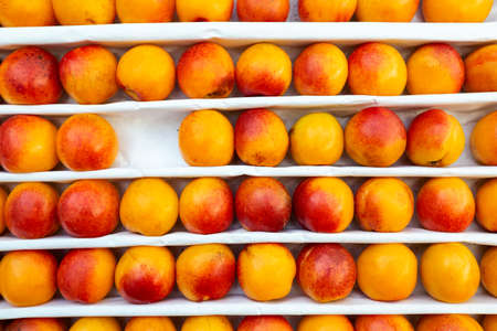A lot of peaches in box on sale at farms market. Top view. Food backgroundの写真素材