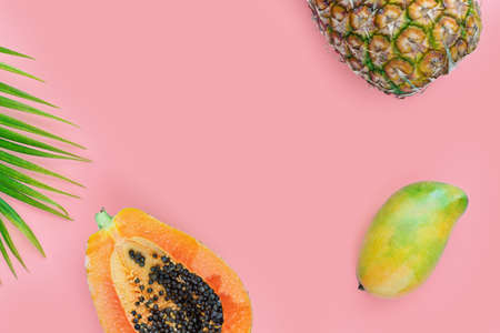 Tropical fruits on pink color background. Pineapple, papaya, and mango flat lay. Summer food conceptの写真素材