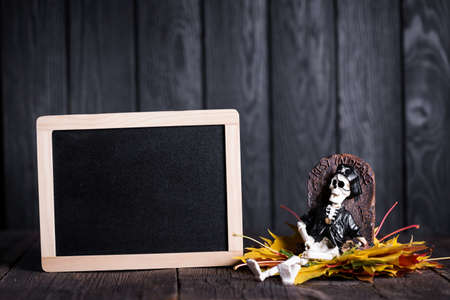 Halloween toy of skeleton with grave and chalkboard on wooden background, nobodyの写真素材