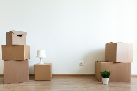 Different cardboard boxes for moving at room interior movement or delivery concept, empty wall with...