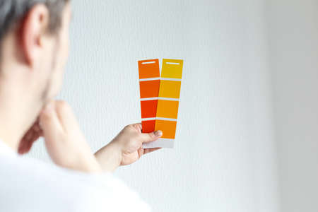 Man designer or architect choosing wall color from color palette guide, colorful swatches in handの写真素材