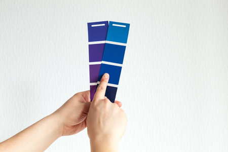 Man designer or architect choosing wall color from color palette guide, colorful swatches in hand