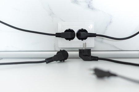 A lot of black cord plugs running to european white socket. Electrical dependence concept