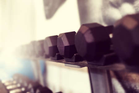 Black color dumbbell weights in fitness center. Gym equipment. Blurred background for copy space. Shallow depth.の写真素材