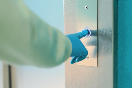 Hand in a rubber glove presses the elevator or lift button. Personal protection against bacteria and...