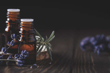 Collection of different blank amber bottles with essential oils on wooden board with dry lavender sprigs. Aromatherapy and spa conceptの写真素材