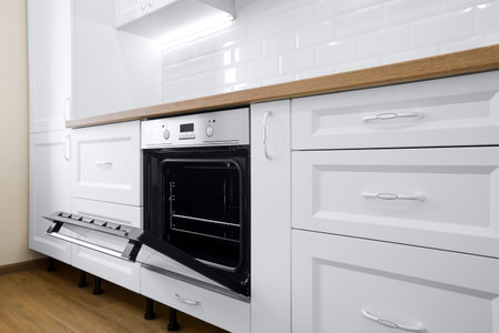 Modern cooking stove in white kitchen interior with tiled wall and wooden countertop, nobody