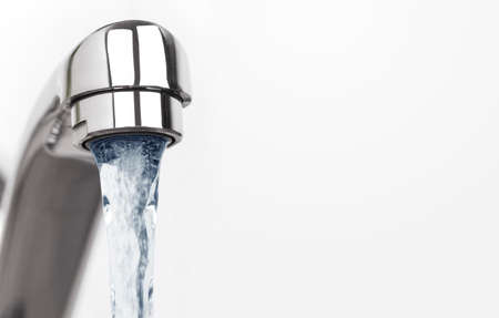 Faucet with water drop on white background with copy spaceの写真素材