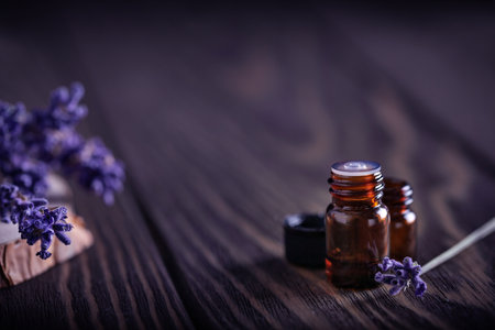 Amber bottles with essential oils on dark wooden background decorated lavender flowersの写真素材