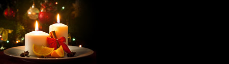New Year decoration, candles, cinnamon sticks and pieces of orange, on christmas tree background. Long bannerの写真素材