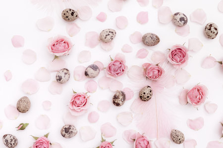 Easter holiday card, flatlay pattern composition with quail eggs, pink feathers and roses petal on...