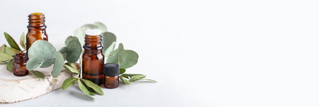 Different branches of eucalyptus leaves with blank amber bottles. Botanical herbs and dark glass jars on neutral background. Aromatherapy for booster immune and air purifier, header bannerの写真素材