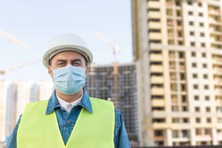 Worker staff or engineer in protective helmet and medical mask protect himself from covid-19 at construction site during coronavirus epidemicの写真素材