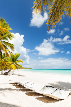 Beach calm scene with sunbeds under coconut palms close to Caribbean sea. Tropical paradise with...