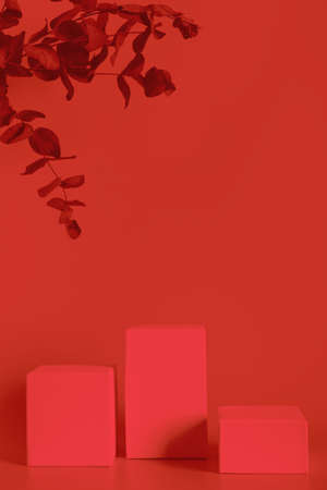 Red toned empty stands on color background decorated eucalyptus leaves. Blank podiums shopfront. Showcase for cosmetic or beauty promotions. Product display advertisement. Copy space.の写真素材