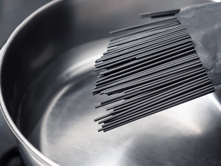 Uncooked black spaghetti above saucepan. Ready to cook dark pastaの写真素材