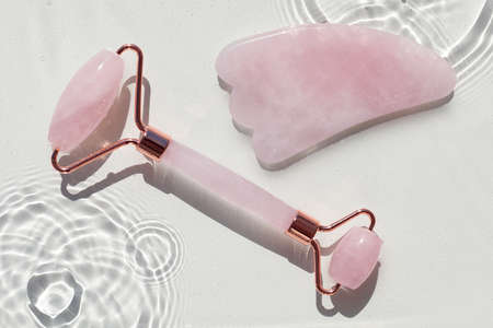 Quartz roller and guasa on abstract water texture, surface with drops, rings and ripple. Flat lay, top view, alternative skincare background with copy spaceの写真素材