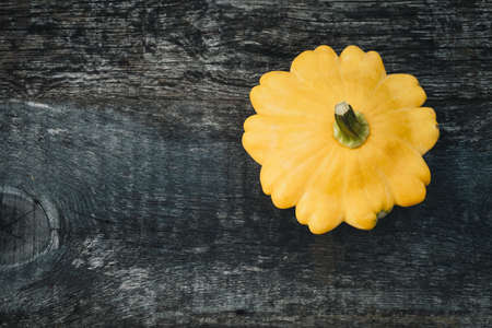 One pattypan vegetable on old wooden board, top viewの写真素材