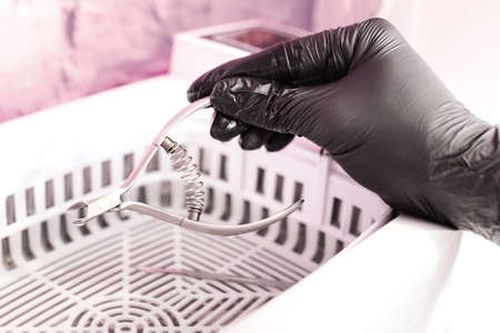 Putting manicure tools into sterilizer machine. Professional manicurist in gloves disinfecting instruments for nail care procedure. Beauty conceptの写真素材