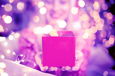 Happy woman in Santa Claus hat opening and surprising with pink gifts box. Unboxing presents in...