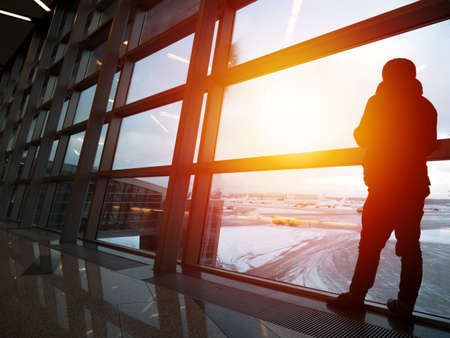 Silhouette of unrecognizable man waiting the flight in airport departure terminal. Travel conceptの写真素材