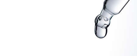 Drop of water falling from glass lab pipette isolated on white background. Macroの写真素材