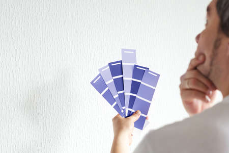 Man designer or architect choosing wall color from color palette guide, colorful swatches in hand. Trendy colors of the year 2022 - Very Periの写真素材