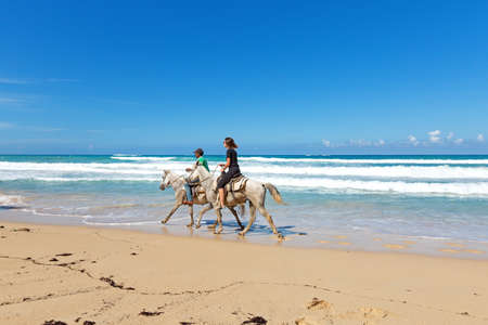 PUNTA CANA, DOMINICAN REPUBLIC - March 1th, 2019: Tourists on tropical horse riding excursion. Wild caribbean beach Macao of Atlantic ocean with waves, travel destinationsのeditorial素材