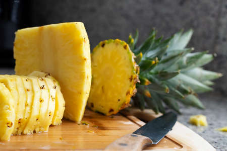 Sliced pineapple on wooden board, tropical fruit on kitchen topの写真素材