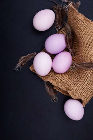 Happy easter holiday card with painted eggs on burlap texture on dark background. Trendy color of 2022 - Very Periの写真素材