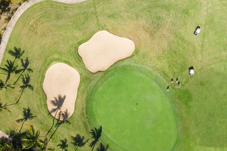 Golf club field with carts and playing golfers. Aerial view from droneの写真素材
