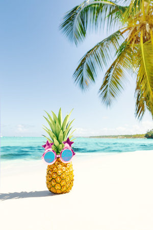Funny pineapple creative face in funky sunglasses on caribbean vacations. Exotic fruit on beach close to sea on coconut palm leaf backdrop. summer backgroundの写真素材