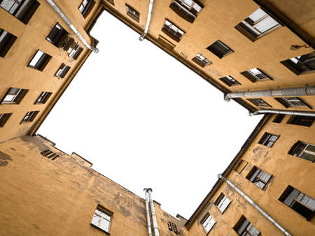 Yard well in old city. Yard-well hole with yellow walls and gray sky. up viewの写真素材