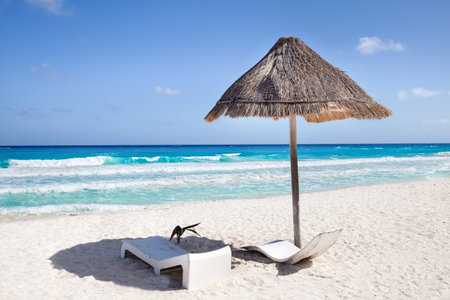 Sun umbrella ans sunbed on white sandy beach with turquoise ocean water. Caribbean sea travel destination. Bounty and pristine nature for vacation. Nobodyの写真素材