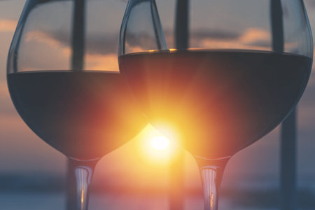 Two wineglasses with red wine with sun light through glasses on sunset. Nobody