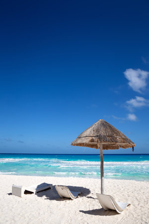 Sun umbrella ans sunbed on white sandy beach with turquoise ocean water. Caribbean sea travel destination. Bounty and pristine nature for vacation. Nobodyの写真素材