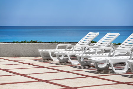 Lounge sunbeds near swimming pool, outdoor near caribbean seaの写真素材