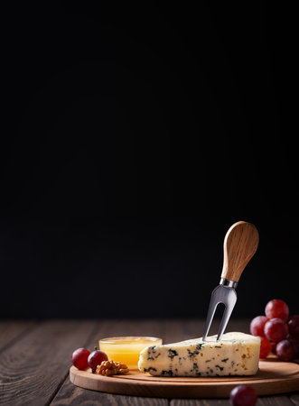 Piece of blue cheese woth fork on slatter on dark wooden background, copy spaceの写真素材