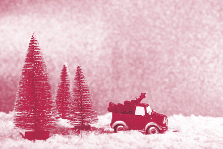 Christmas Car carrying fir tree with New Year spruce trees on snow. winter holidays. Viva Magenta color of the year 2023の写真素材