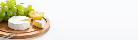 Sliced Camembert with fork on wooden cheese platter on white background. long bannerの写真素材