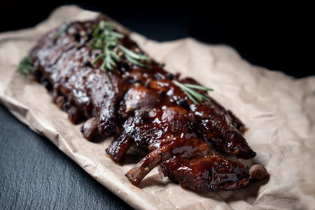 Pork grilled ribs with rosemary and pepper on craft paper on dark background.の写真素材