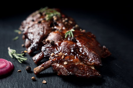 Pork grilled ribs with rosemary and pepper on craft paper on dark background.の写真素材