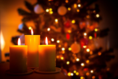 Christmas burning candles on garland lights blurred background, selective focus, decorative New Year 2023 card with copy spaceの写真素材
