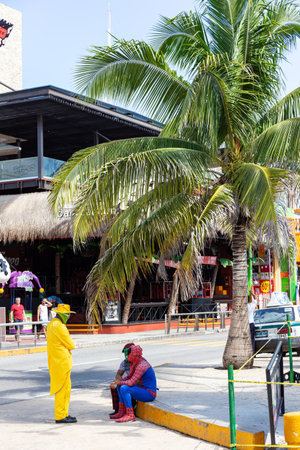 Cancun, Mexico - 29 October 2015: Animators in Spider man and Mask suits resting under palm tree in the street near Coco Bongo clubのeditorial素材