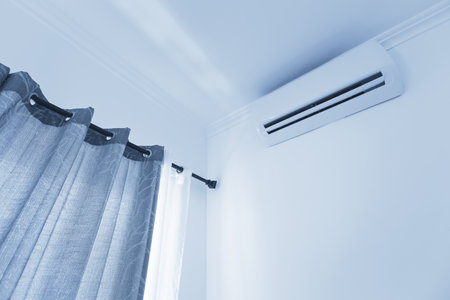 Flat air conditioner on white wall in room interior, nobody. blue toneの写真素材