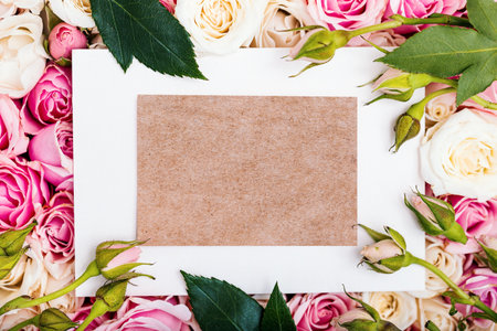 Empty craft paper card with copy space on floral background, zero waste invitation decorated with roses buds, holiday or celebration conceptの写真素材