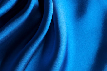 Crop of blue atlas satin material background, silk abstract textile surface, drapery clothの写真素材